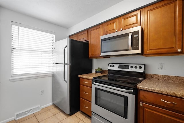 kitchen featuring stainless steel appliances and light tile patterned flooring