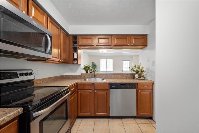 kitchen featuring sink, light tile patterned floors, a textured ceiling, and appliances with stainless steel finishes