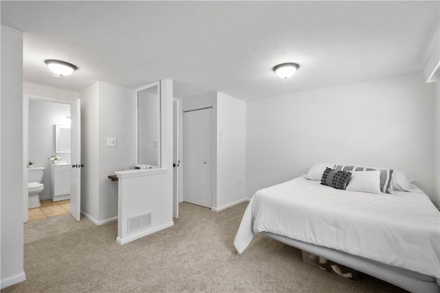 bedroom featuring ensuite bath, a closet, and light carpet