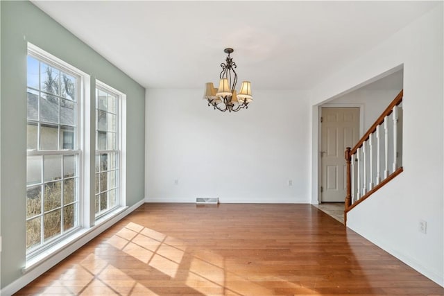 unfurnished dining area featuring a chandelier and light hardwood / wood-style flooring