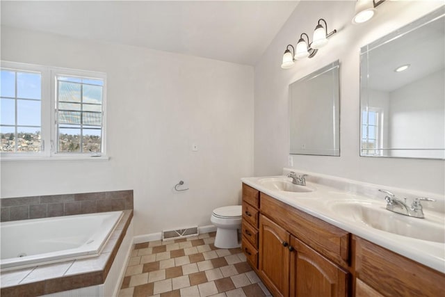 bathroom with a relaxing tiled tub, plenty of natural light, toilet, and vanity