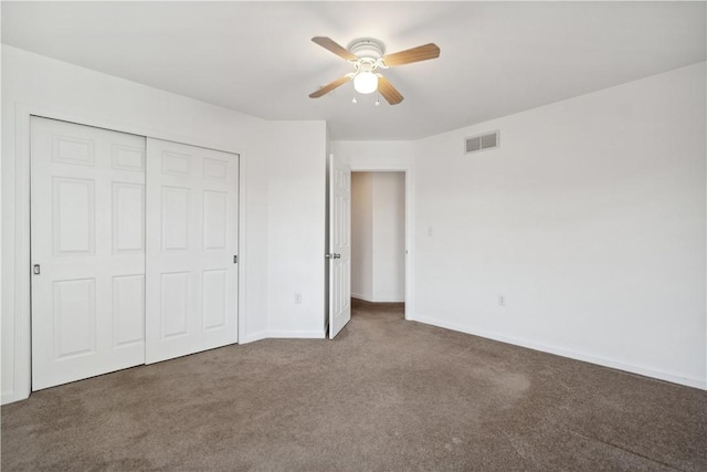 unfurnished bedroom featuring ceiling fan, dark carpet, and a closet