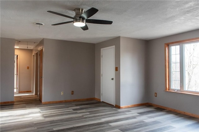 unfurnished room with ceiling fan, light hardwood / wood-style flooring, and a textured ceiling