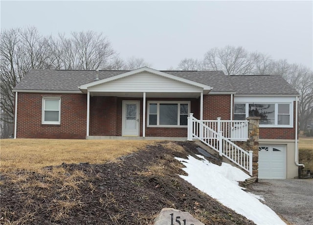 ranch-style home with roof with shingles, a front lawn, a porch, and brick siding