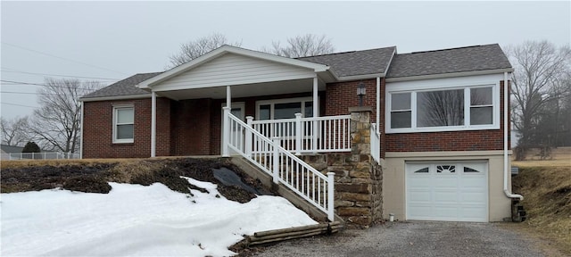 ranch-style house with covered porch, brick siding, an attached garage, and roof with shingles