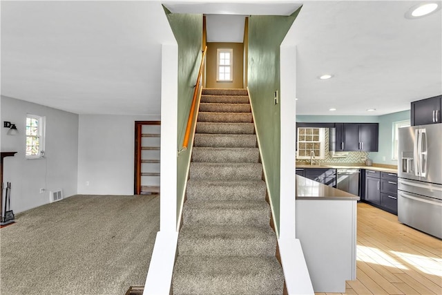 stairway featuring hardwood / wood-style flooring, sink, and a wealth of natural light