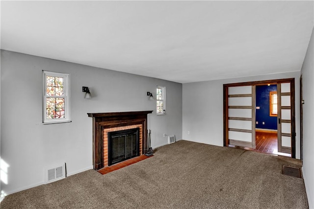 unfurnished living room with a brick fireplace and carpet floors