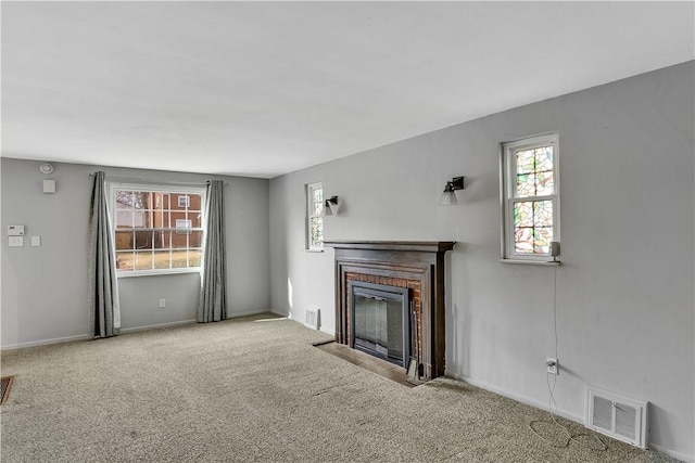 unfurnished living room featuring light carpet and a brick fireplace