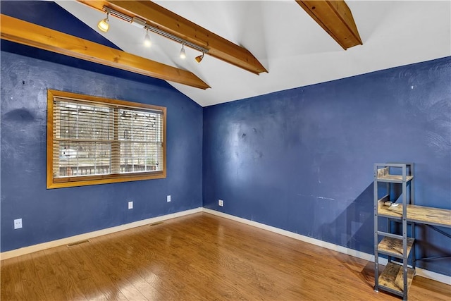 empty room with wood-type flooring and vaulted ceiling with beams