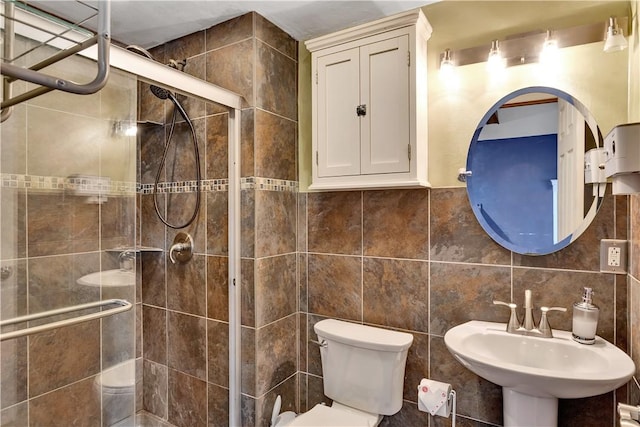 bathroom featuring toilet, sink, tile walls, and a shower with shower door