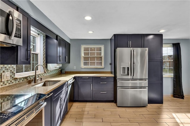 kitchen featuring tasteful backsplash, sink, light stone counters, and stainless steel appliances