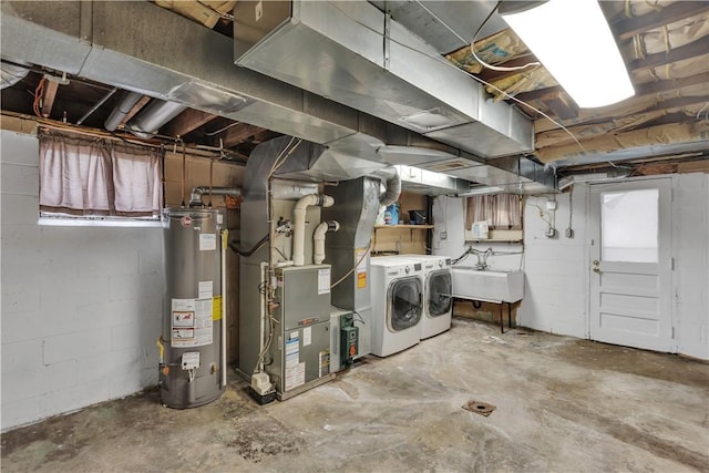 basement featuring heating unit, sink, gas water heater, and washing machine and clothes dryer