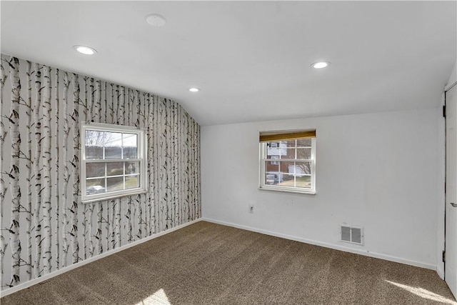 carpeted spare room featuring a healthy amount of sunlight and vaulted ceiling