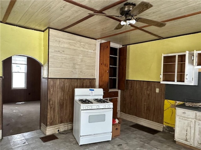 kitchen featuring wood walls, white cabinetry, ceiling fan, gas range gas stove, and wooden ceiling