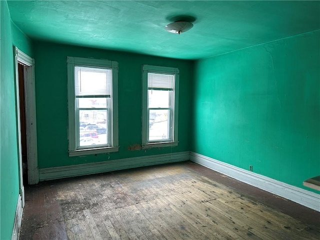 spare room featuring baseboard heating and hardwood / wood-style flooring