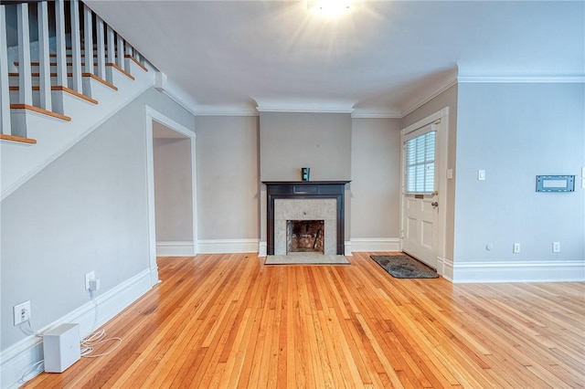 unfurnished living room with a tile fireplace, crown molding, and light wood-type flooring