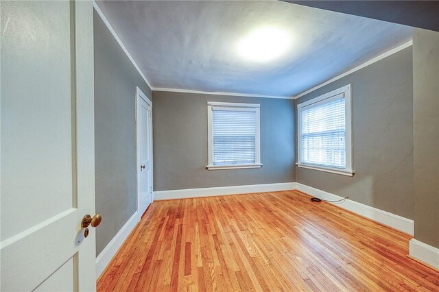 spare room with ornamental molding and light wood-type flooring