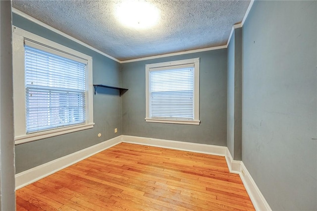 spare room with crown molding, a textured ceiling, and light wood-type flooring