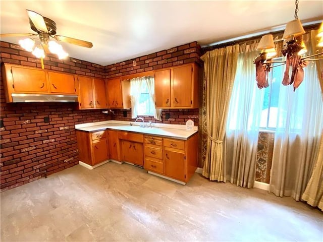 kitchen with ceiling fan with notable chandelier, brick wall, decorative light fixtures, and sink