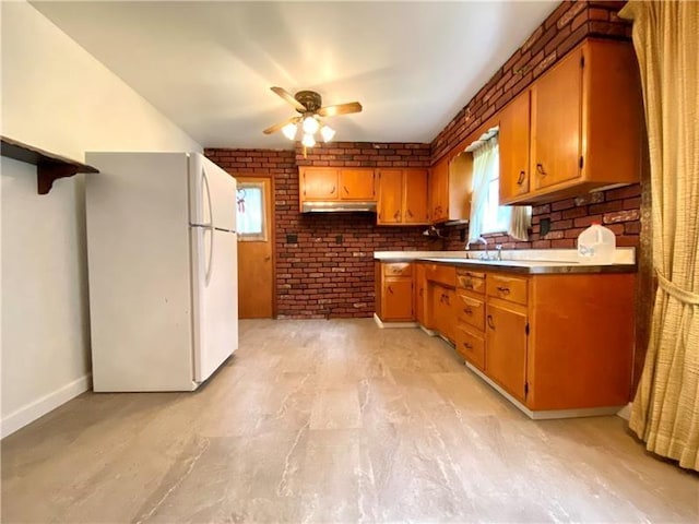 kitchen with brick wall, white fridge, and ceiling fan