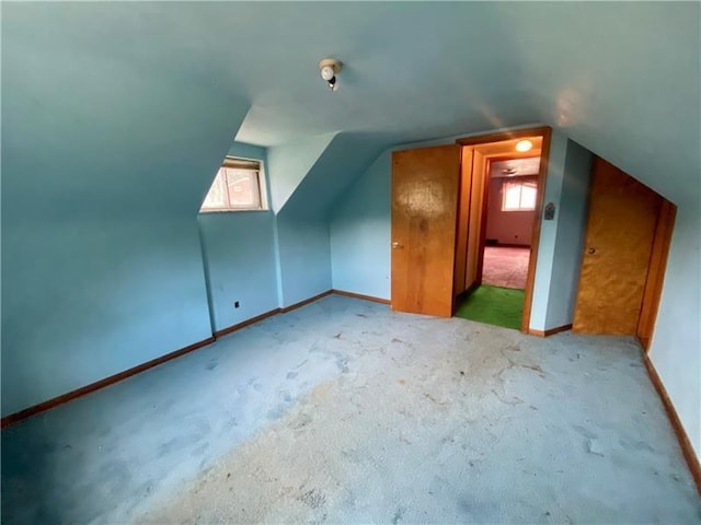 bonus room with vaulted ceiling, light colored carpet, and a healthy amount of sunlight