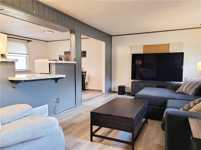 living room with crown molding and light wood-type flooring