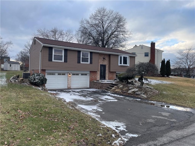 bi-level home featuring a garage, a front yard, and central air condition unit