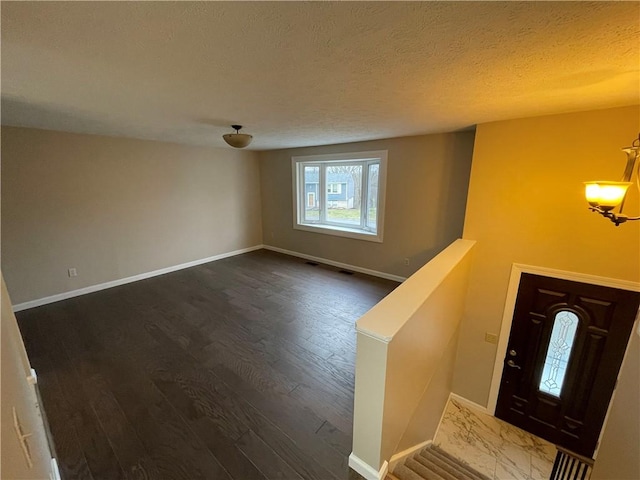 foyer entrance with dark hardwood / wood-style floors and a textured ceiling