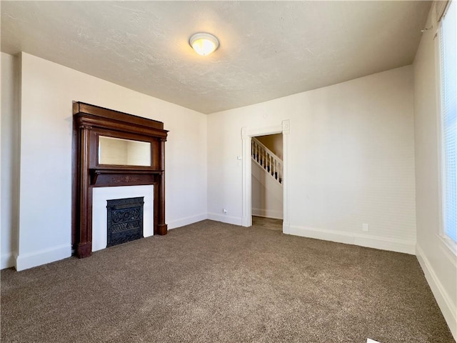 unfurnished living room with a fireplace, baseboards, and carpet flooring