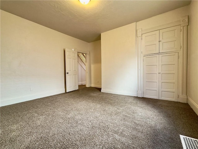 unfurnished bedroom with carpet floors, a closet, visible vents, and baseboards