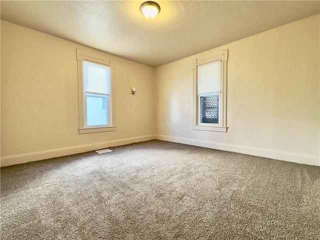 spare room featuring carpet floors, visible vents, and baseboards