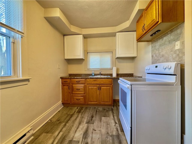 kitchen featuring electric stove, brown cabinets, light wood-style floors, a healthy amount of sunlight, and a sink