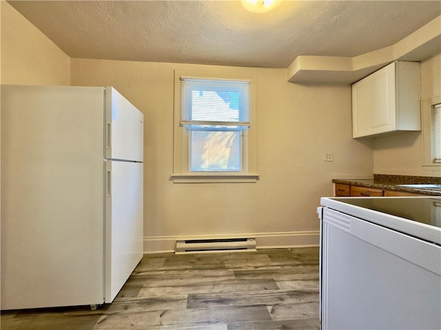 kitchen featuring white cabinetry, baseboard heating, light wood-type flooring, freestanding refrigerator, and dark countertops