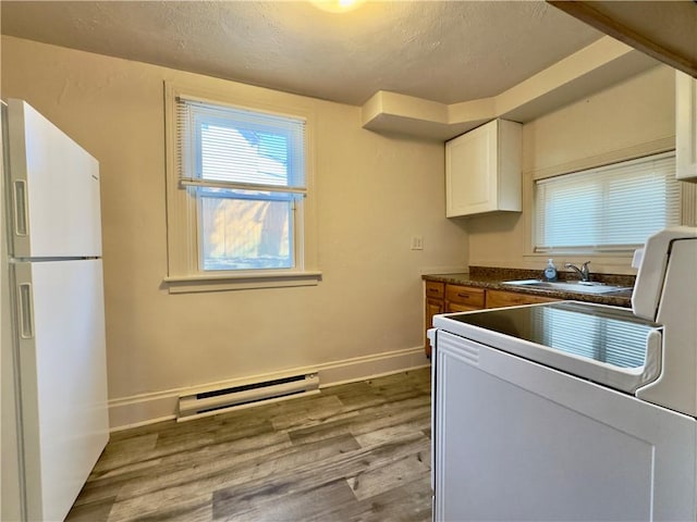 kitchen with white appliances, baseboards, white cabinets, light wood-style floors, and baseboard heating