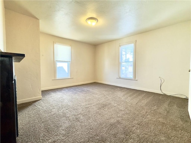 unfurnished living room with baseboards and carpet flooring