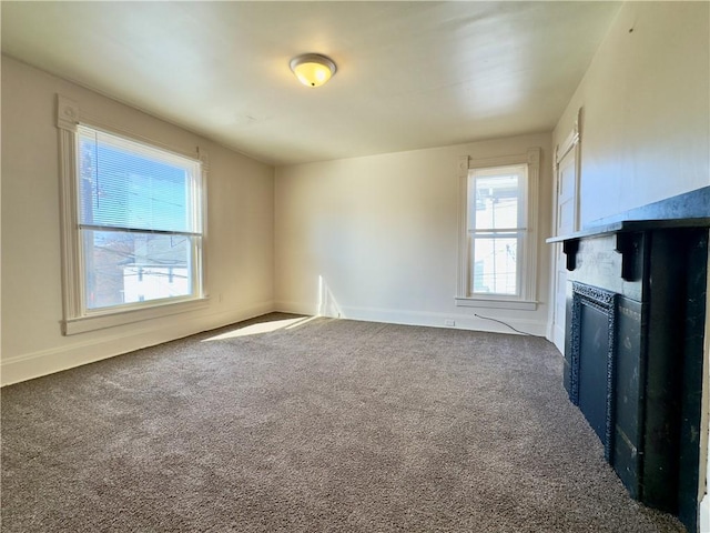 unfurnished living room with dark colored carpet, a fireplace, and baseboards