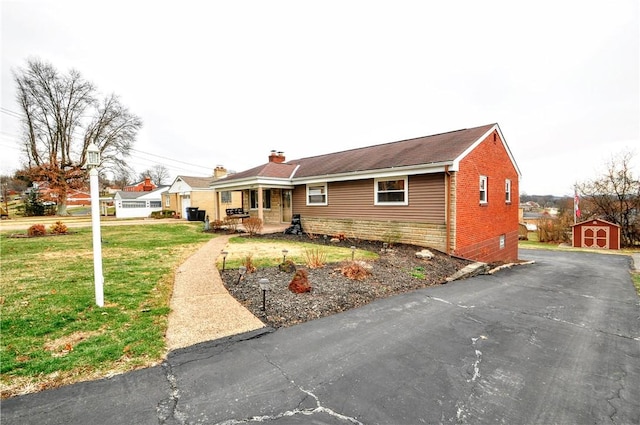 view of front of property featuring a storage unit, covered porch, and a front lawn