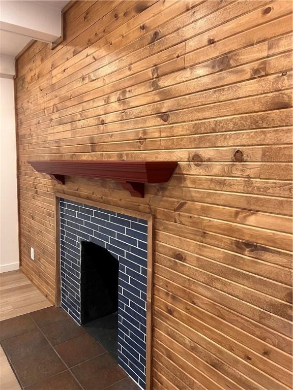 details with a tile fireplace and wood walls