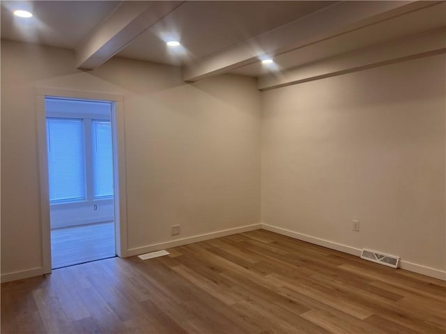 spare room with hardwood / wood-style floors and beam ceiling