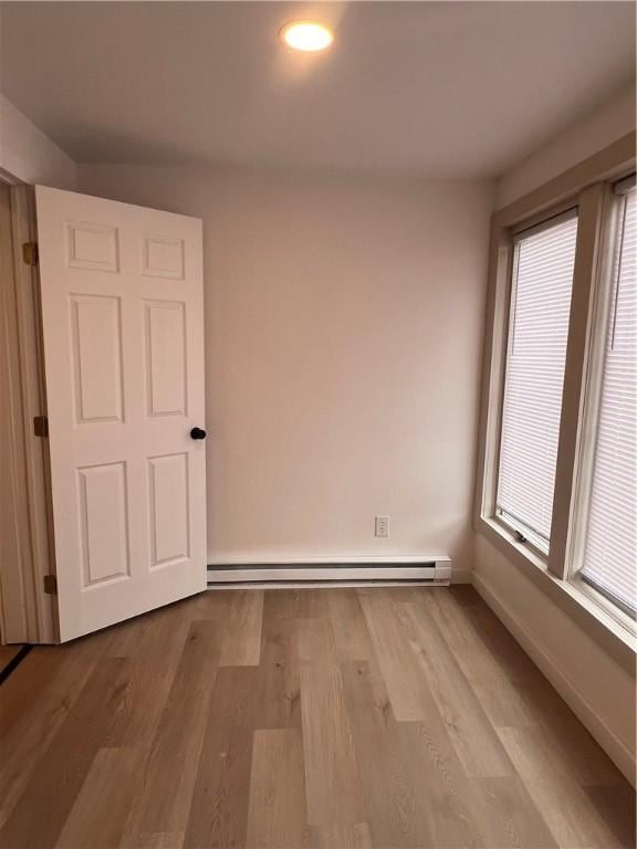 empty room with a baseboard radiator and light hardwood / wood-style floors