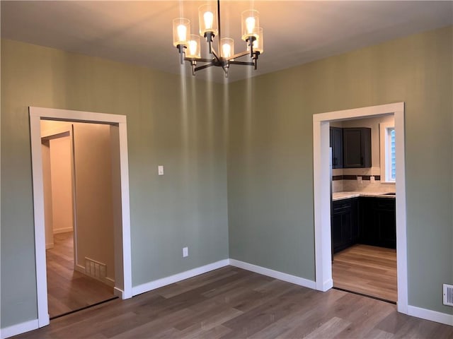 empty room featuring hardwood / wood-style floors and a notable chandelier