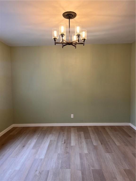 empty room with an inviting chandelier and hardwood / wood-style floors