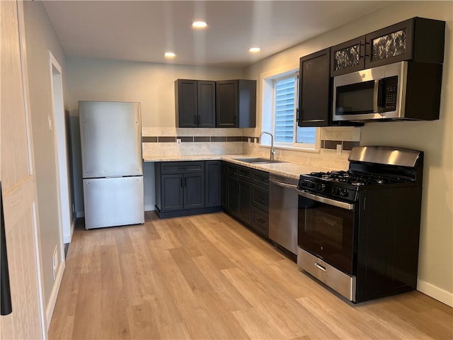 kitchen featuring appliances with stainless steel finishes, sink, backsplash, and light hardwood / wood-style floors