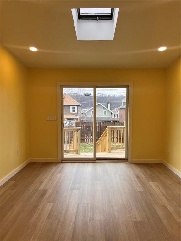 spare room with a skylight and hardwood / wood-style floors