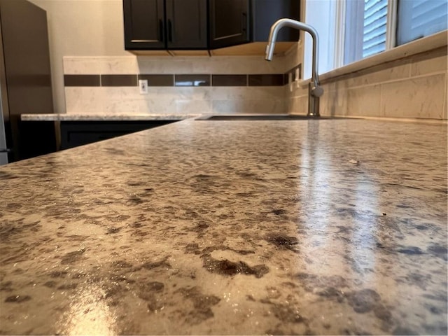 room details with tasteful backsplash, sink, and light stone counters