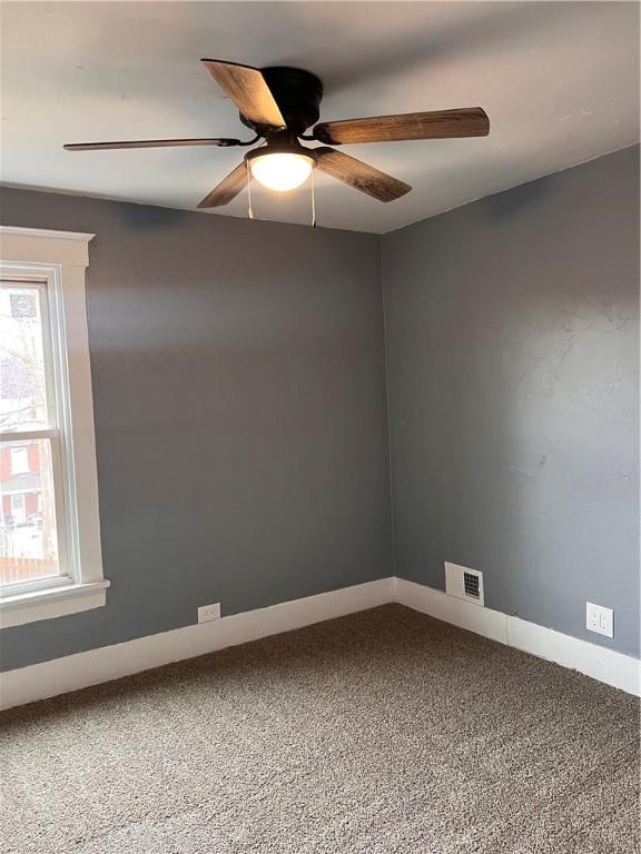 spare room featuring carpet floors, a wealth of natural light, and ceiling fan