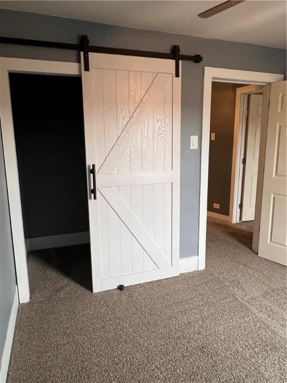 interior space with a barn door, carpet floors, and ceiling fan