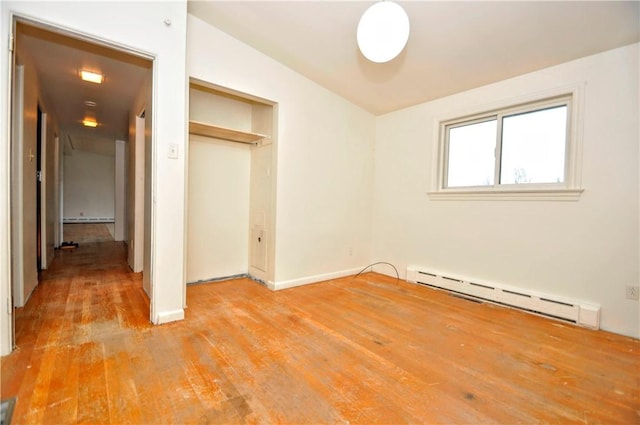 unfurnished bedroom with a closet, baseboard heating, and light hardwood / wood-style flooring