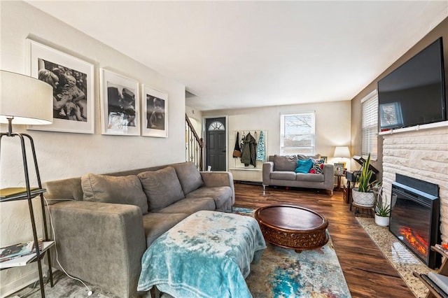 living room featuring a stone fireplace and dark hardwood / wood-style floors