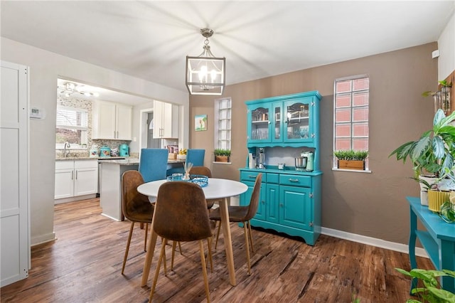 dining room with sink, dark hardwood / wood-style floors, and a chandelier